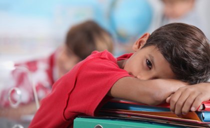 Image: Adobe Stock Young boy resting his head on books